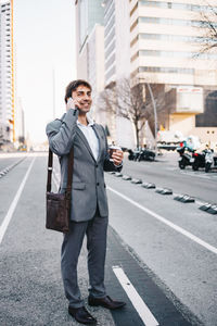 Full length of businessman talking on phone while standing on road