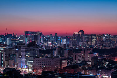 Illuminated buildings in city against sky at sunset