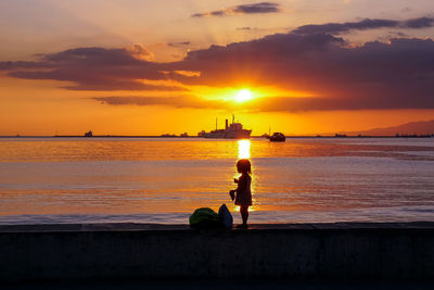 Silhouette people on beach against sky during sunset