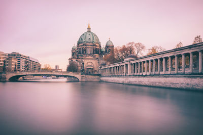 Arch bridge over canal by berlin cathedral against clear sky at dusk