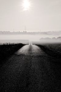 Empty road field against sky during foggy weather