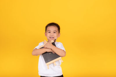 Portrait of happy boy standing against yellow background