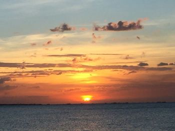 Scenic view of sea against dramatic sky during sunset