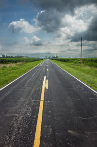 Empty road against cloudy sky