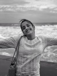 Portrait of smiling man standing at beach against sky