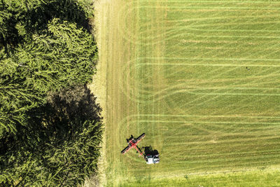 Aerial view of tractor moving green field in early spring