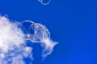 Low angle view of soap bubbles against blue sky