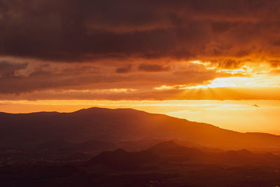 Orange and yellow colors, sunrise over island, mountains with sun rays.