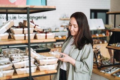 Adult smiling brunette woman choosing sweets in cafe, woman having shopping in confectionery
