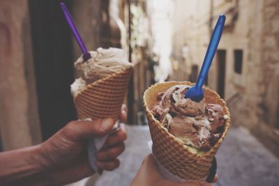 Close-up of hands holding ice cream cone at city