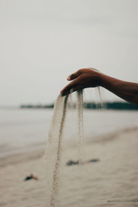 Person holding umbrella on beach against clear sky