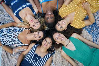 Group of smiling female friends lying on a towel in a park