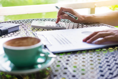 Cropped hands of woman using calculator on table