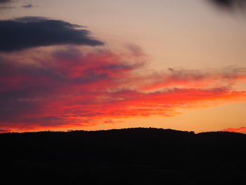 Silhouette landscape against dramatic sky during sunset