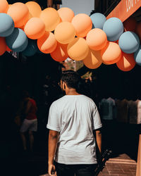 Rear view of man with balloons standing at night