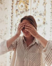 Young woman standing against curtain at home