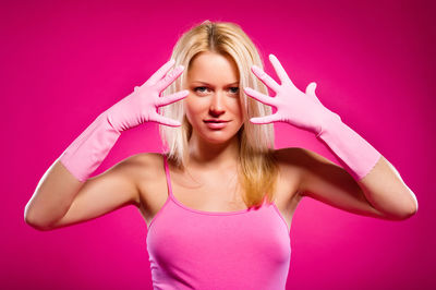 Portrait of pregnant woman exercising standing against pink background