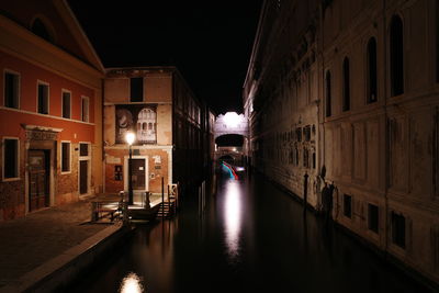 Canal amidst buildings in city at night