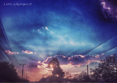 Low angle view of power lines against cloudy sky