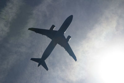 Low angle view of airplane against cloudy sky