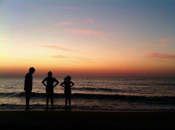 Silhouette people on beach against sky during sunset