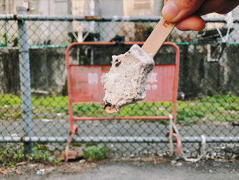 Cropped hand holding fence against blurred background