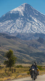 Couple on touring motorbike. lanin volcano in the back, argentina
