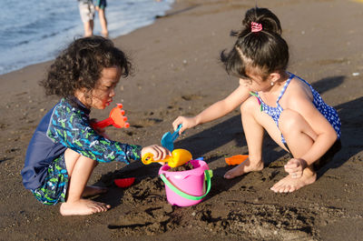 Girl with sister playing with toys at beach