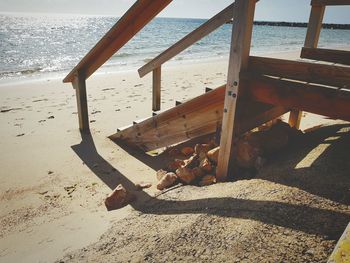 Cat relaxing on sand at beach against sky