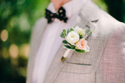 Midsection of bridegroom wearing boutonniere on suit