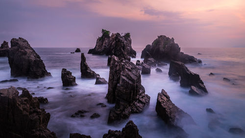 Panoramic view of rocks on sea against sky during sunset