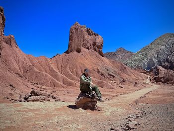 Rear view of man standing on mountain against clear blue sky