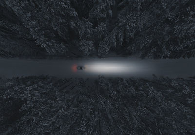 A car drives along a snow-covered road in  snowy forest. top view. themes of road trips and vehicles