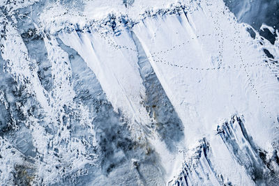 Snow shattered over the ice lake with traces of animals, top view