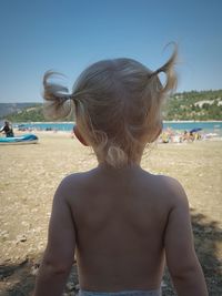 Rear view of woman at beach against sky