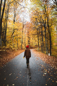 Rear view of woman walking on road during autumn