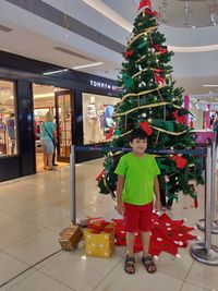 Full length of boy standing by christmas tree