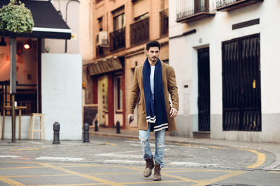 Full length of man walking on street against building