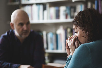 Close-up of crying mature patient sitting with therapist at home office