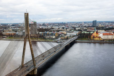 Bridge over river in city against cloudy sky