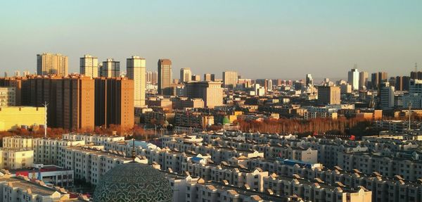 Aerial view of buildings in city against clear sky