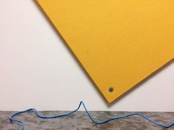 Close-up of blue cable by yellow metal over floor