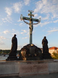 Statue of cross against sky