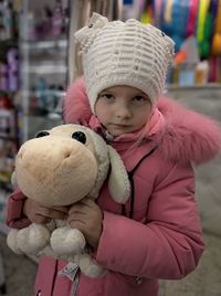 Portrait of cute girl holding stuffed toy while standing in store 