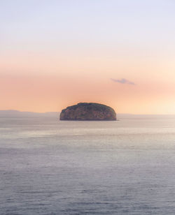 Scenic view of rocks in sea against sky during sunset