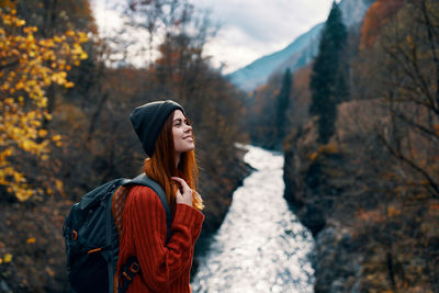 Young woman looking away while standing on land during autumn