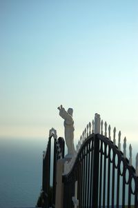 Statue by sea against clear sky