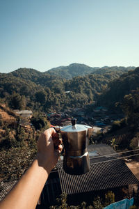 Hand holding coffee cup against clear sky