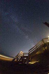 Low angle view of steps at beach against sky at night