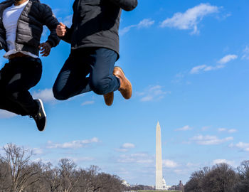 Low angle view of men jumping in city against sky